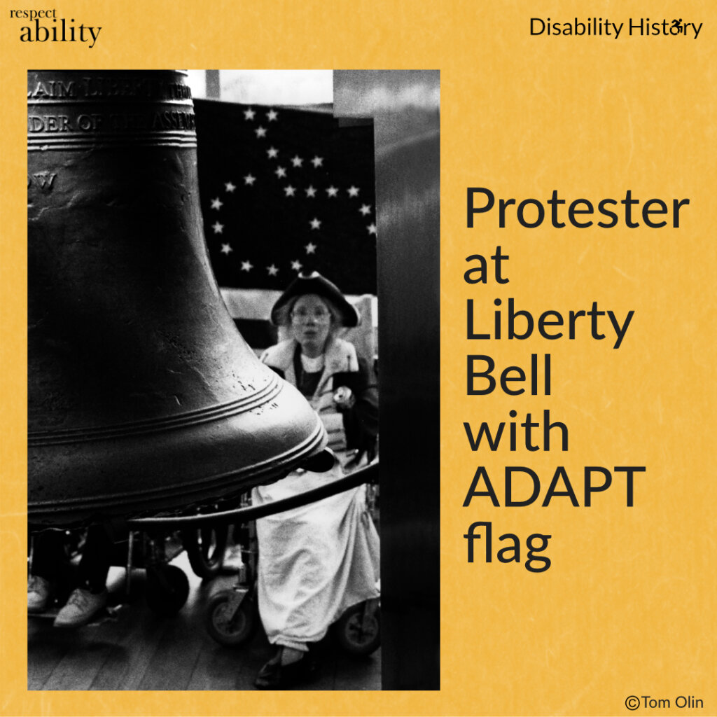 Black and white photo showing part of the liberty bell. Behind the bell is a protester in revolutionary attire in a wheelchair with the ADAPT American Flag behind her. Text: Protester at Liberty Bell with ADAPT flag. Source: Tom Olin.