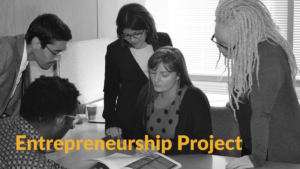 Black and white photo of former RespectAbility fellows looking at a document together around a table. Text: Entrepreneurship Project
