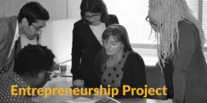 Black and white photo of former RespectAbility fellows looking at a document together around a table. Text: Entrepreneurship Project