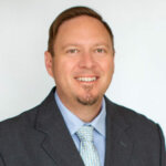 Jarrod Adams smiling headshot wearing a suit and tie