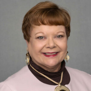 Sharon Gomez smiling headshot with gold earrings and a gold necklace