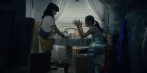 Jeena Yi and Anna Sargent in Take Me Home at a dinner table having an animated conversation