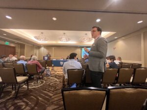 Jimmy Fremgen stands up in a large conference room to ask a question