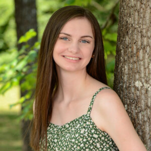 Audrey Bayne smiling headshot standing in front of a tree