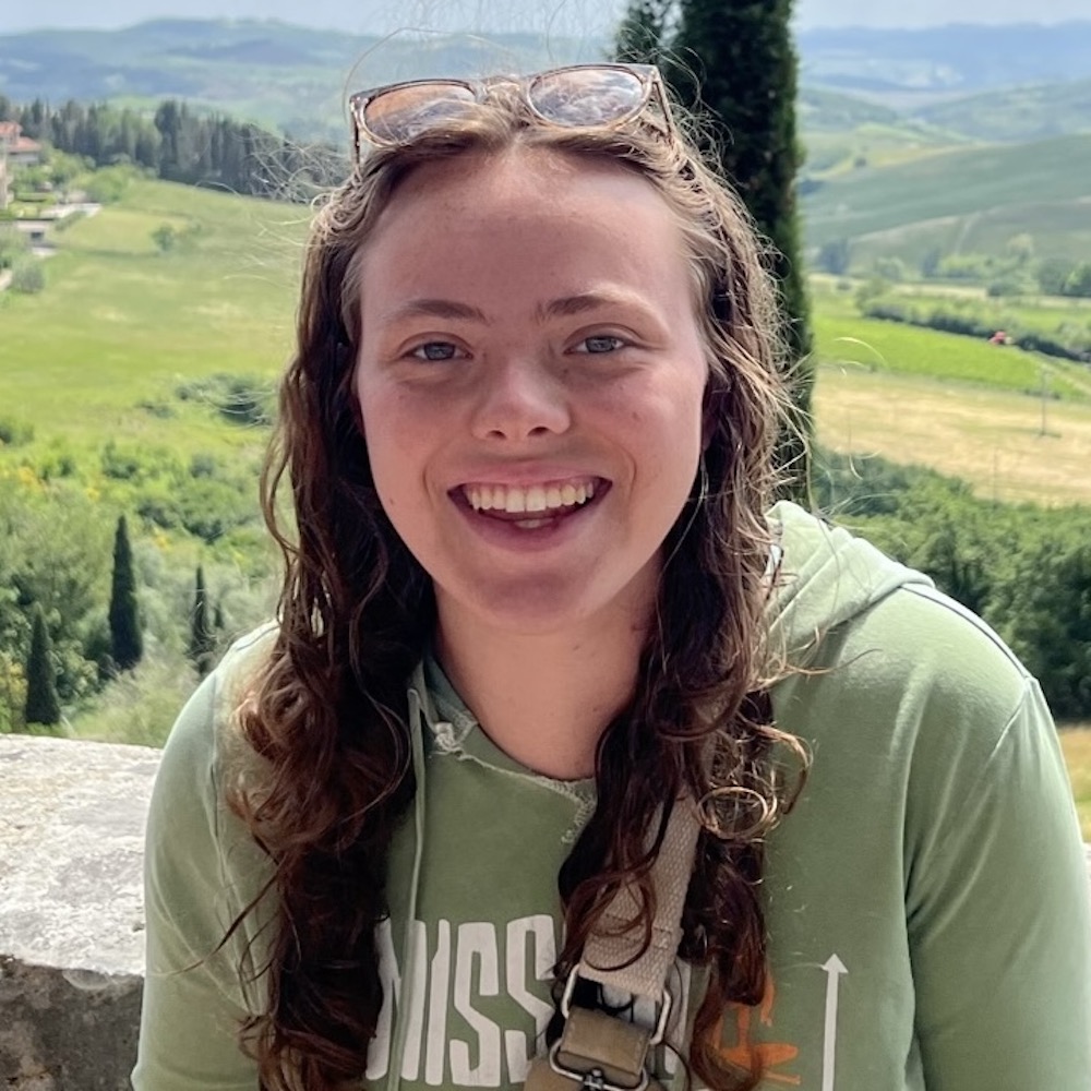 Maddie Jones smiling headshot with mountains behind her