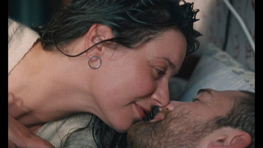 Two people lying in a bed about to kiss in a scene from 