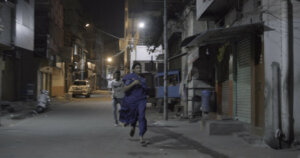A scene from Aleeya with Aleeya running down a street with a man running after her