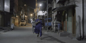 A scene from Aleeya with Aleeya running down a street with a man running after her