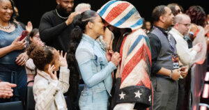 a still from CREED III with Mila Davis-Kent cheering for Michael B. Jordan after a fight as he kisses Tessa Thompson.