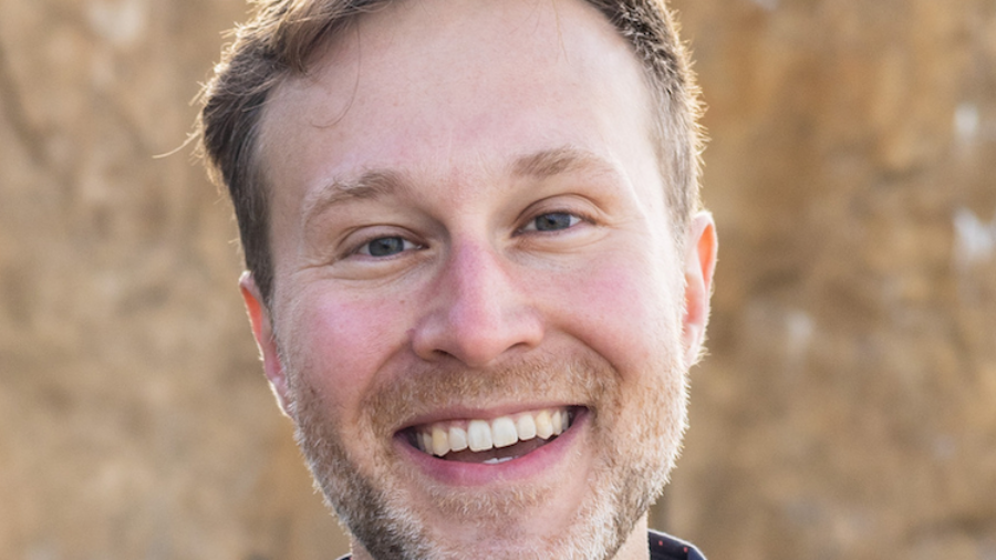 Christopher James smiling headshot wearing a blue dress shirt