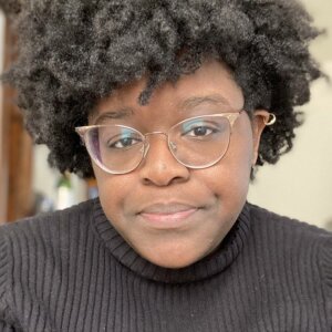 Danielle Monique smiling headshot wearing a dark striped shirt