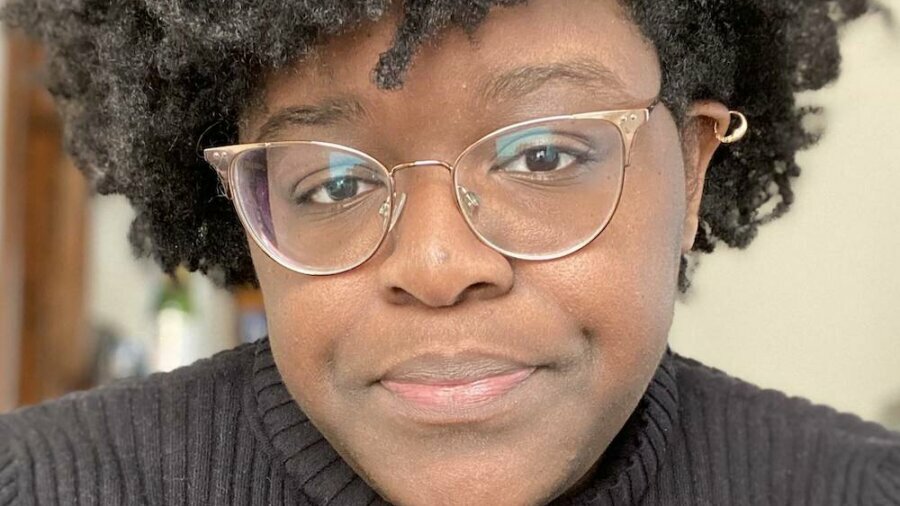 Danielle Monique smiling headshot wearing a dark striped shirt