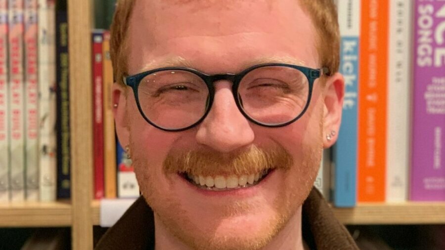 Michael Busza smiling in front of a bookshelf