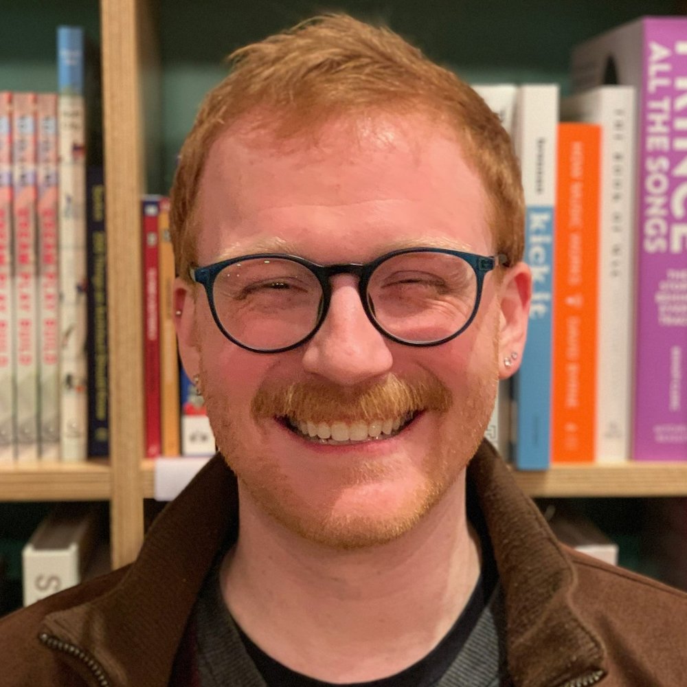 Michael Busza smiling in front of a bookshelf