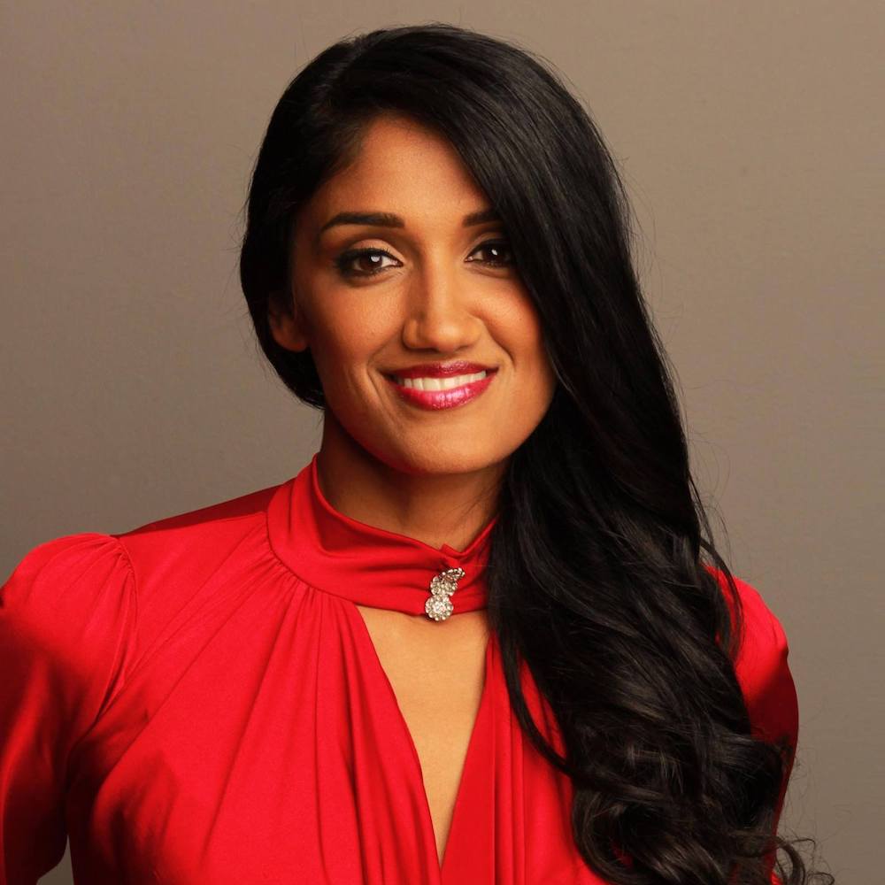 Radha Mehta smiling wearing a red dress