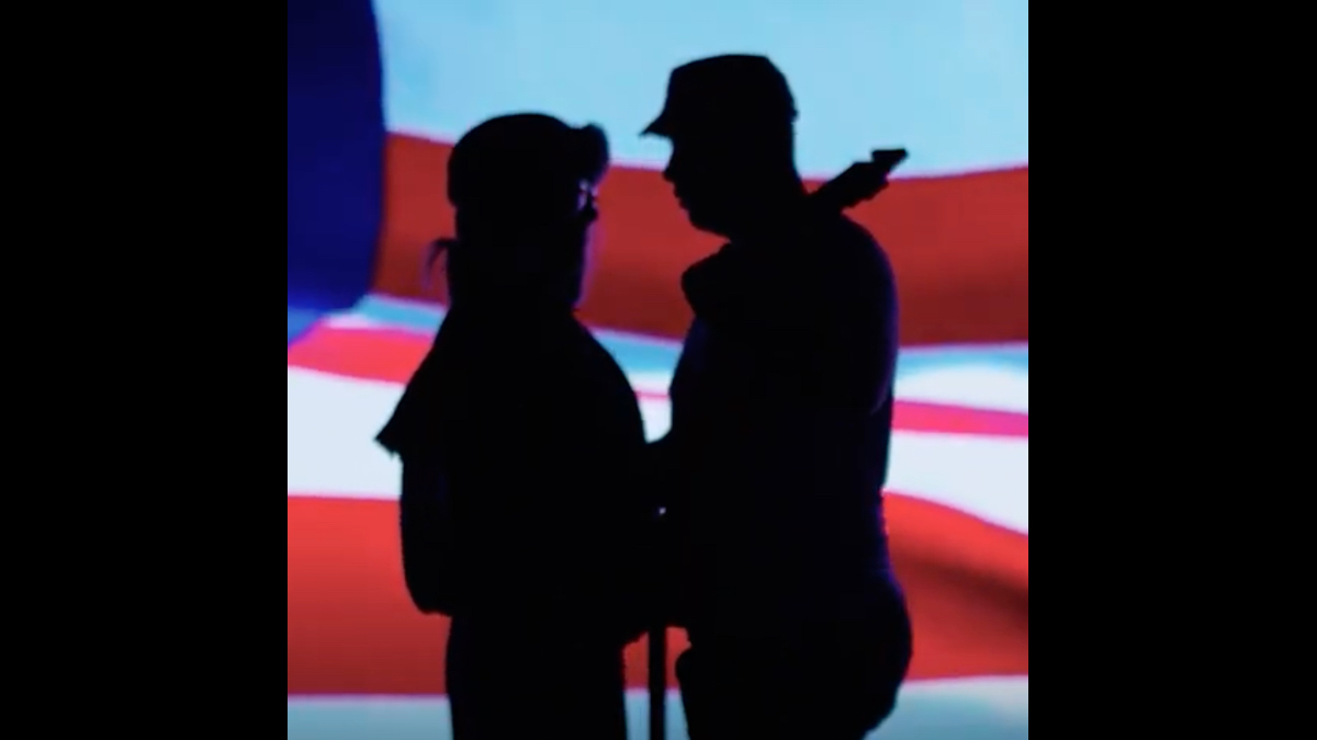 still from "Free As The Wind" with two actors in silhouette in front of an American flag backdrop