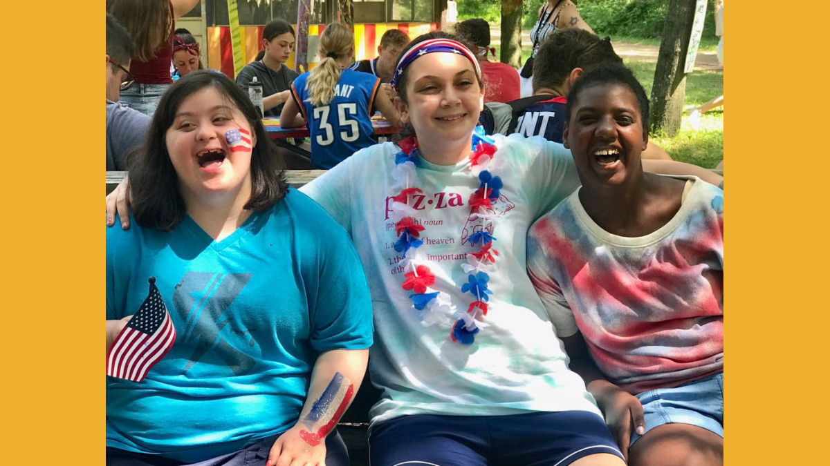 Three girls with disabilities smile together at a Keshet camp
