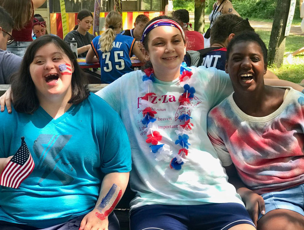 Three girls with disabilities smile together at a Keshet camp