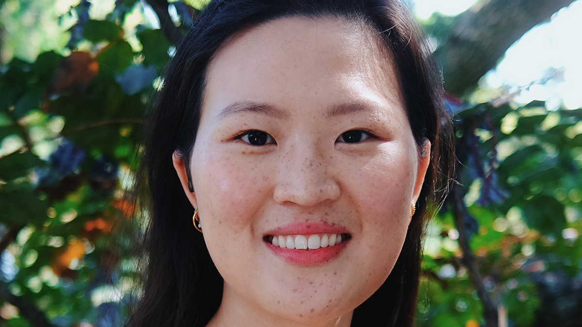 an Asian American woman smiling with greenery in the background