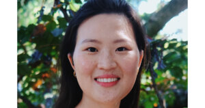 an Asian American woman smiling with greenery in the background