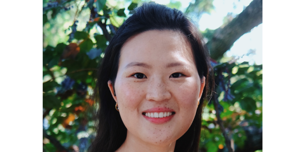 an Asian American woman smiling with greenery in the background