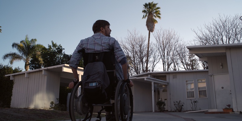 still from Daruma with Tobias Forrest rolling up to a house in his wheelchair