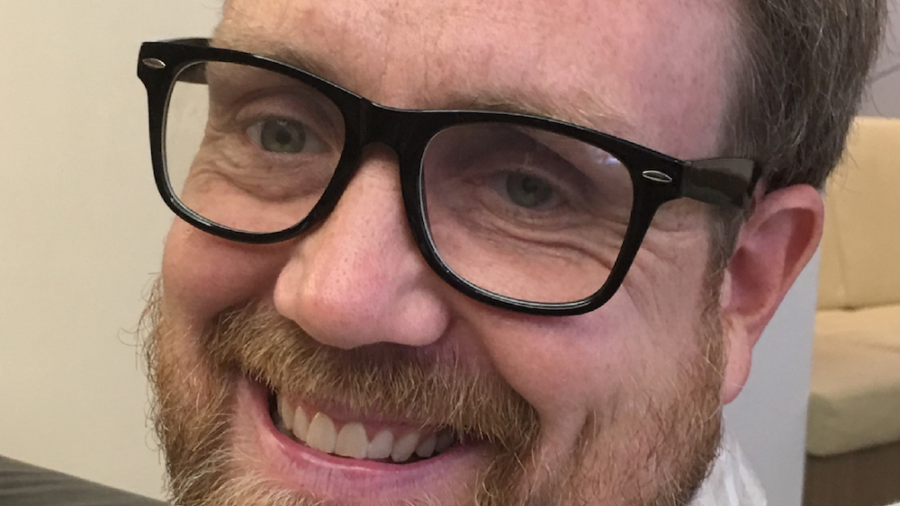 Adam Linn smiling headshot wearing glasses.