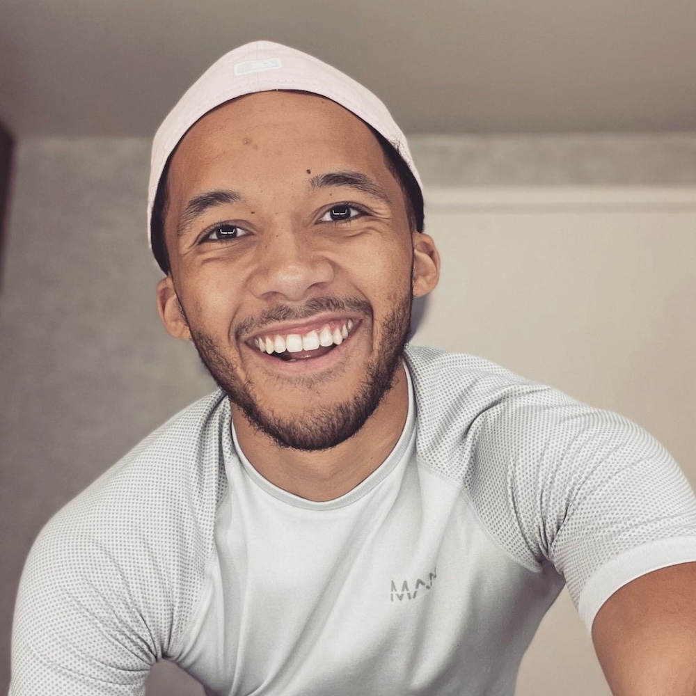 Isaiah Cane smiling headshot wearing a pink hat