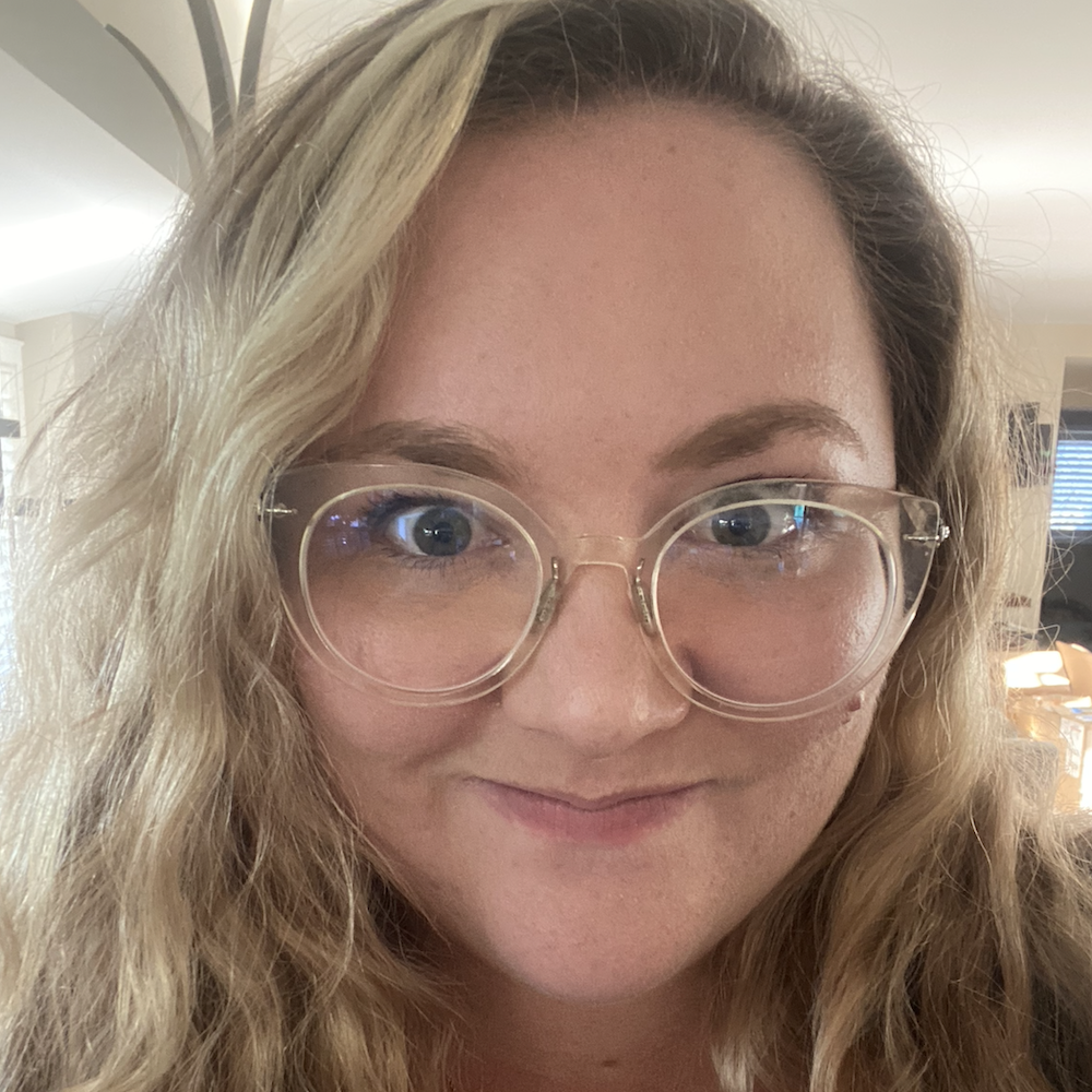 Makena Metz smiling headshot wearing clear glasses