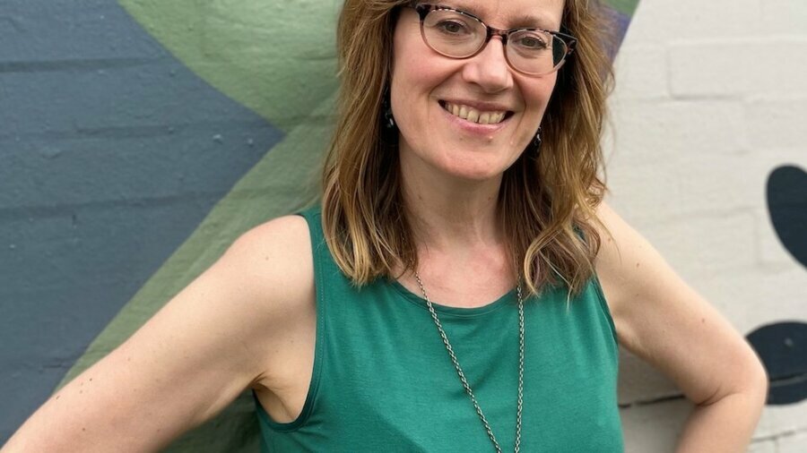 Shannon Rayne smiling in front of a painted brick wall