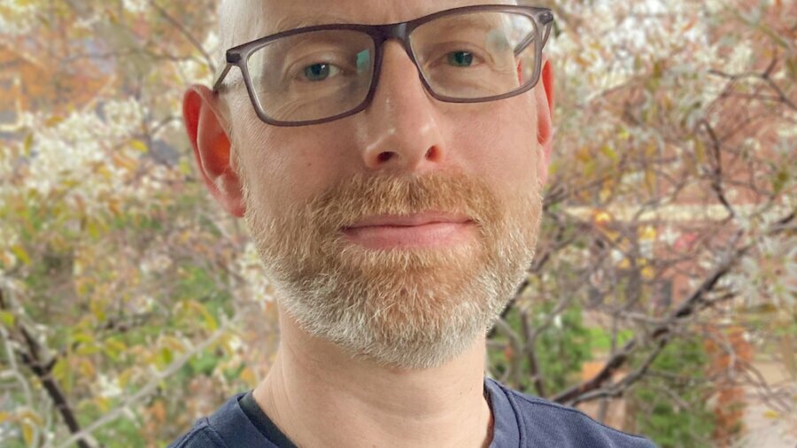Trevor Finn smiling in front of trees wearing glasses