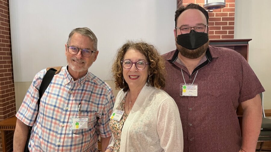 Bill Gaventa, Shelly Christensen, and Ben Bond smile together at the Institute on Theology and Disability. Ben is wearing a face covering.