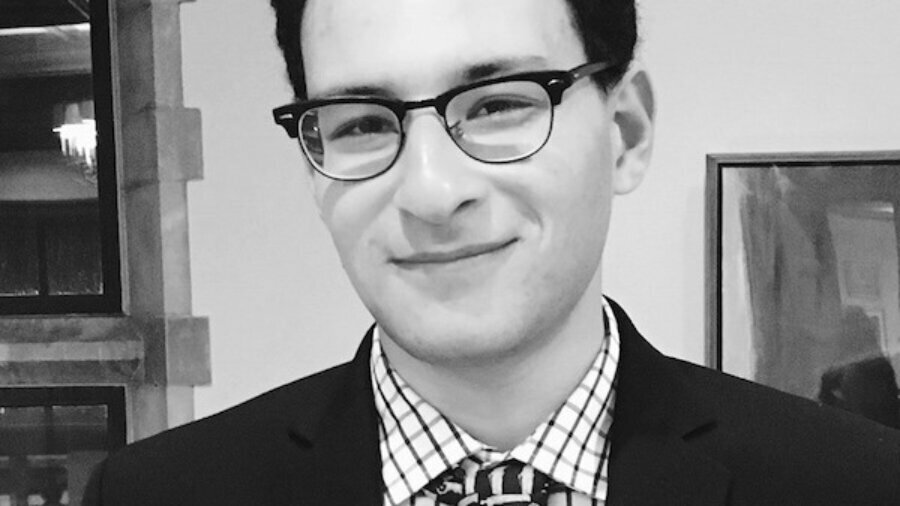 Abe Shaprio smiling headshot wearing glasses, a suit and tie