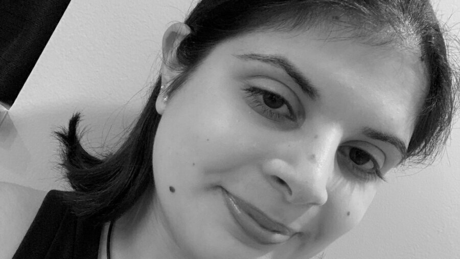 Sara Sharma smiling headshot wearing a necklace and a black shirt
