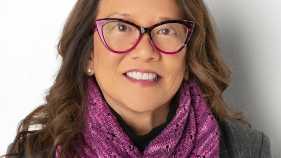 Toby G. Wong headshot smiling wearing glasses and a purple scarf around her neck