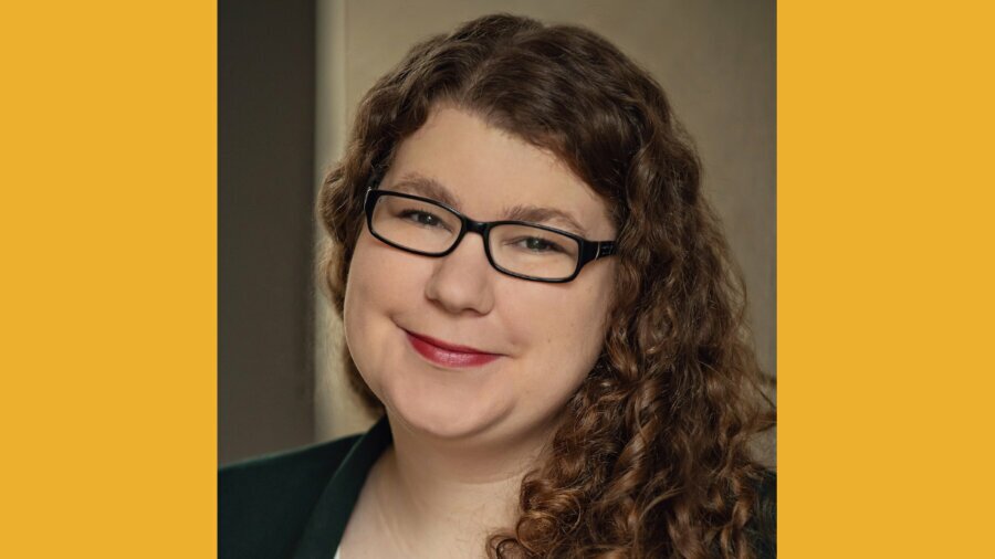 Hannah Roussel smiling headshot wearing a blazer and glasses