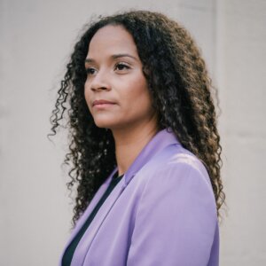 Aisha Becker-Burrowes smiling headshot wearing a purple blazer