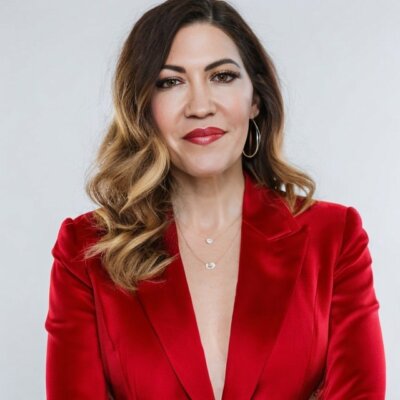 headshot of Stacie wearing bright red lipstick and red blazer