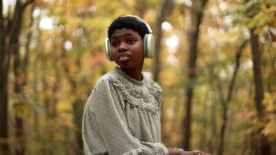 Makayla wearing headphones in the woods in a scene from the documentary