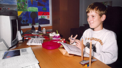 Mats Steen smiling sitting at a desk looking at a computer in a still from Ibelin