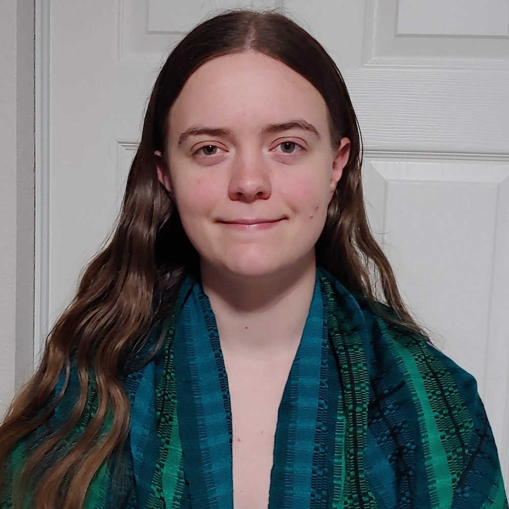 Angela Molloy smiling headshot wearing a blue and green jacket