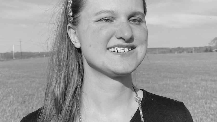 Hannah Harriman smiling headshot standing in front of a grass field