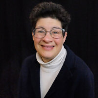 Liz Weintraub smiling headshot in front of a black backdrop
