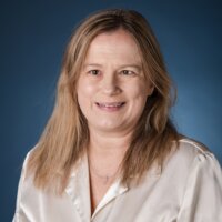 Stacy Cervenka smiling headshot in front of a blue backdrop