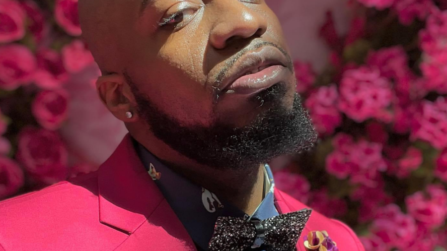 Steven McCoy headshot wearing a pink suit in front of pink flowers