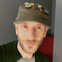 Tom Caulfield smiling headshot with Disney pins on his hat