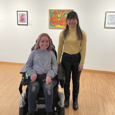 Jessica Hetzel and Ava Rigelhaupt smile together in an art gallery at the JCC in Detroit