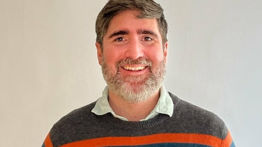 David Dineen-Porter smiling headshot wearing a gray sweater with colorful stripes