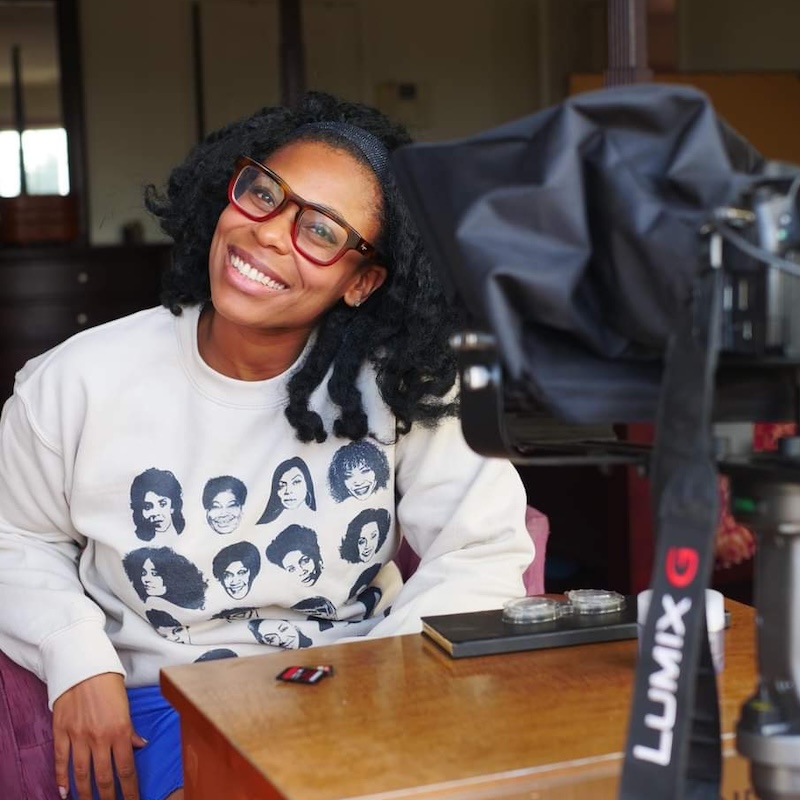 Jacquelyn Revere smiling headshot sitting behind a camera