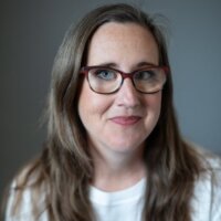 Katherine Craft headshot wearing a white shirt and glasses